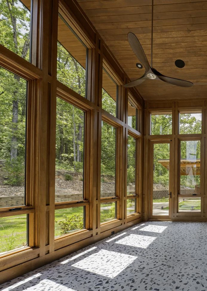 A sunroom surrounded by windows brings the landscape into everyday life.